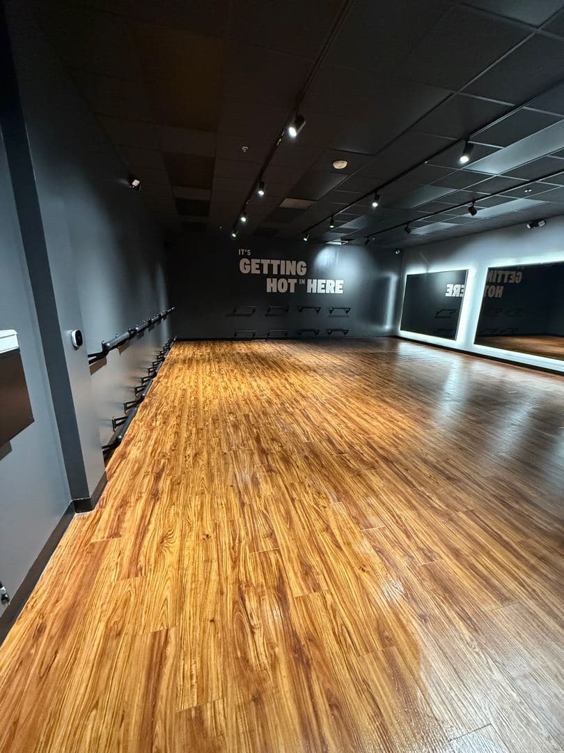 Hot yoga studio with warm wood floor and mirrors, ready for turnover