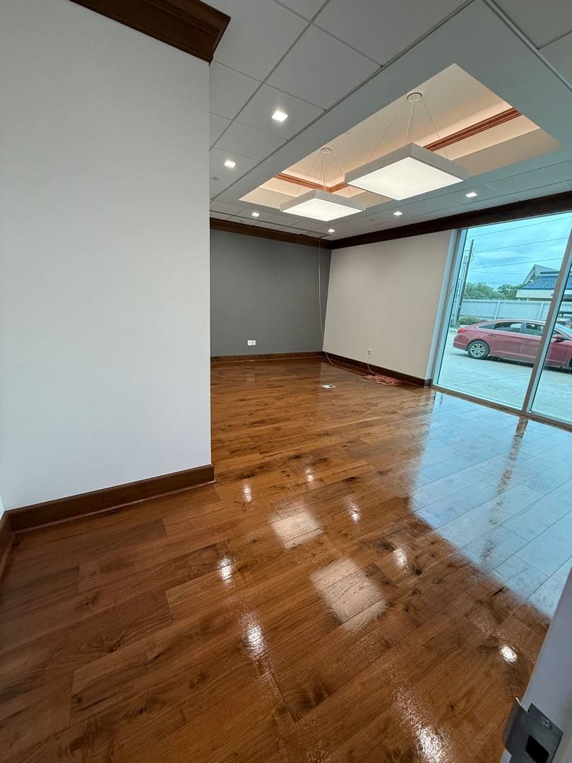 Executive office with glossy hardwood floor and glass wall