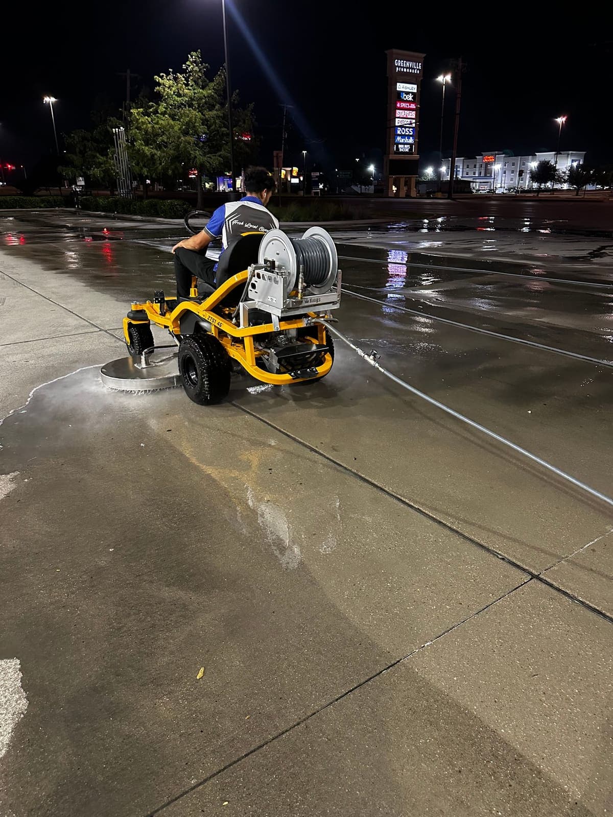 Ride on pressure washer working a retail center at night